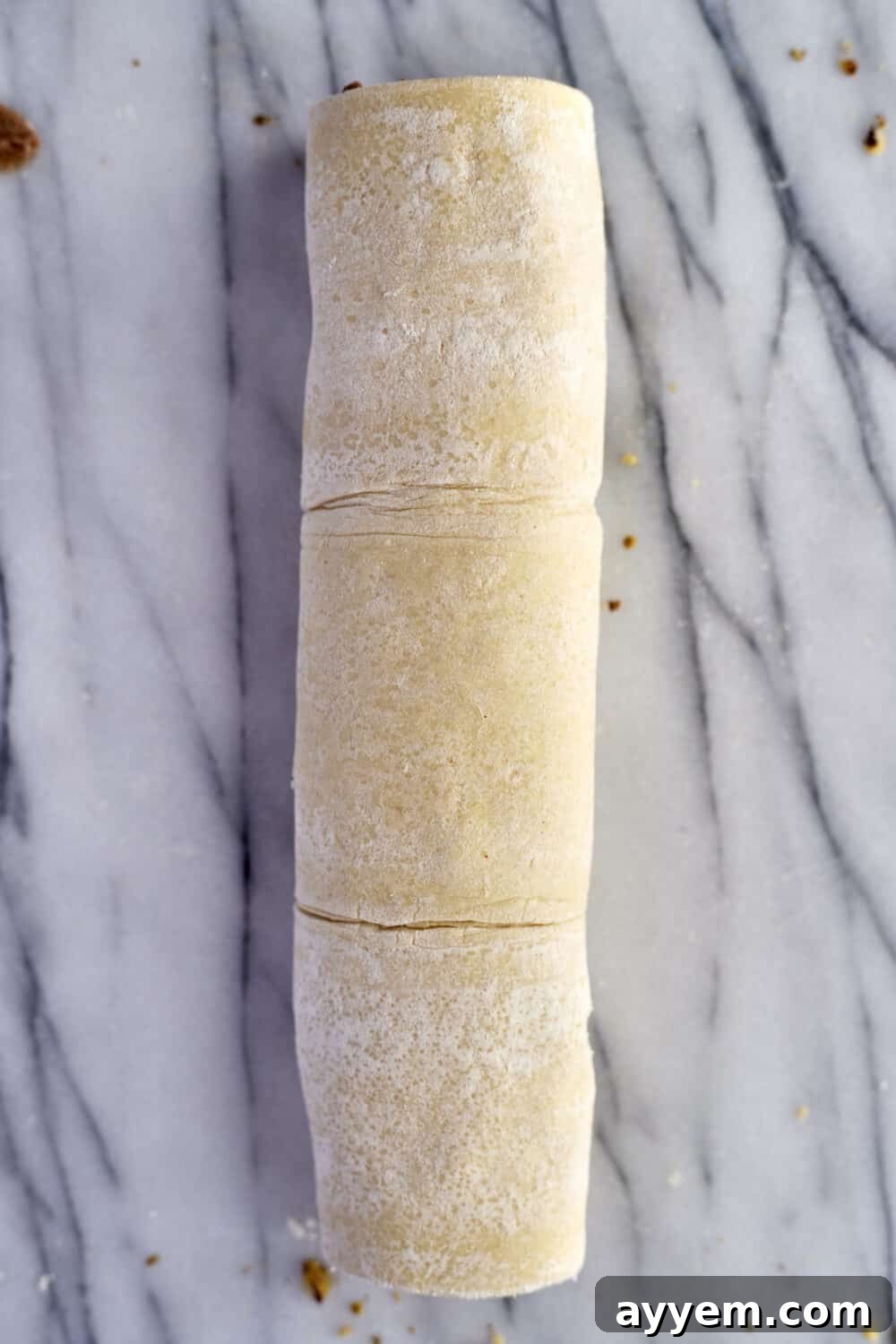 Preparation step 4: Puff pastry being rolled tightly.