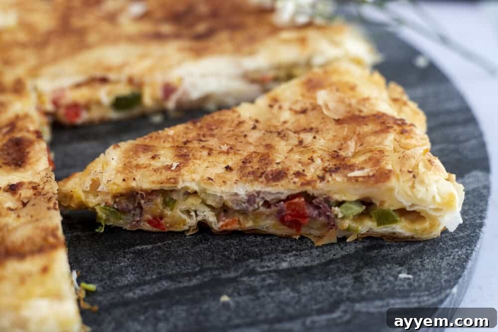 A side view of a generous slice of skillet veggie phyllo pie, highlighting its layers and inviting texture.