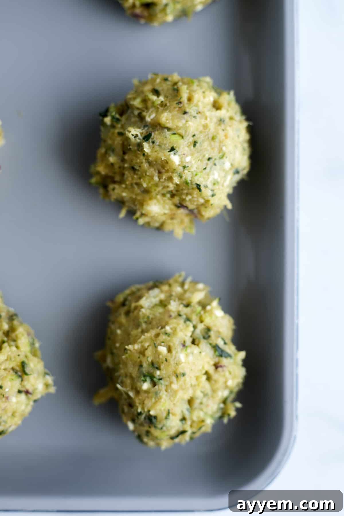 raw Greek meatballs on a baking sheet