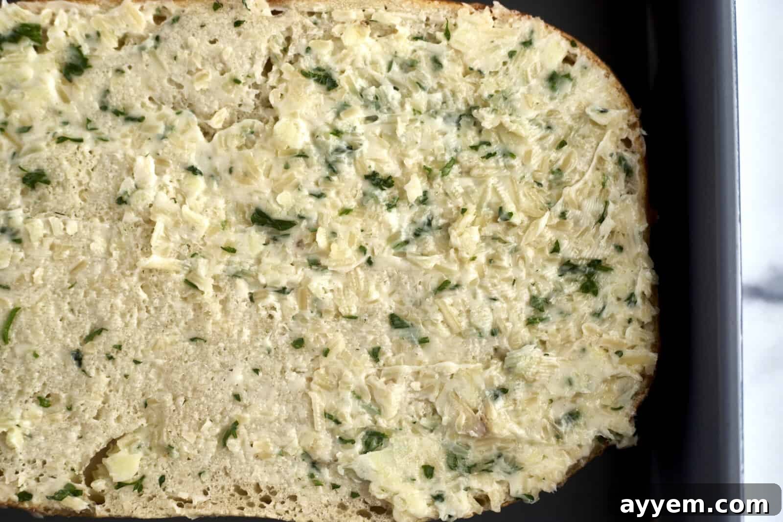 Unbaked bread topped generously with a fragrant garlic butter mixture