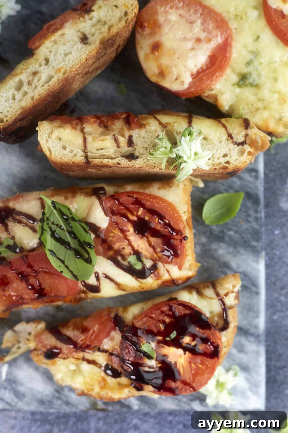 Close-up of baked garlic caprese bread slices, showcasing melted cheese and fresh tomatoes