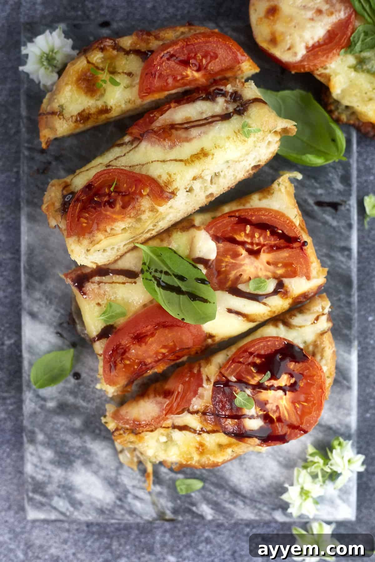 Slices of golden-brown Caprese Garlic Bread, garnished with fresh basil