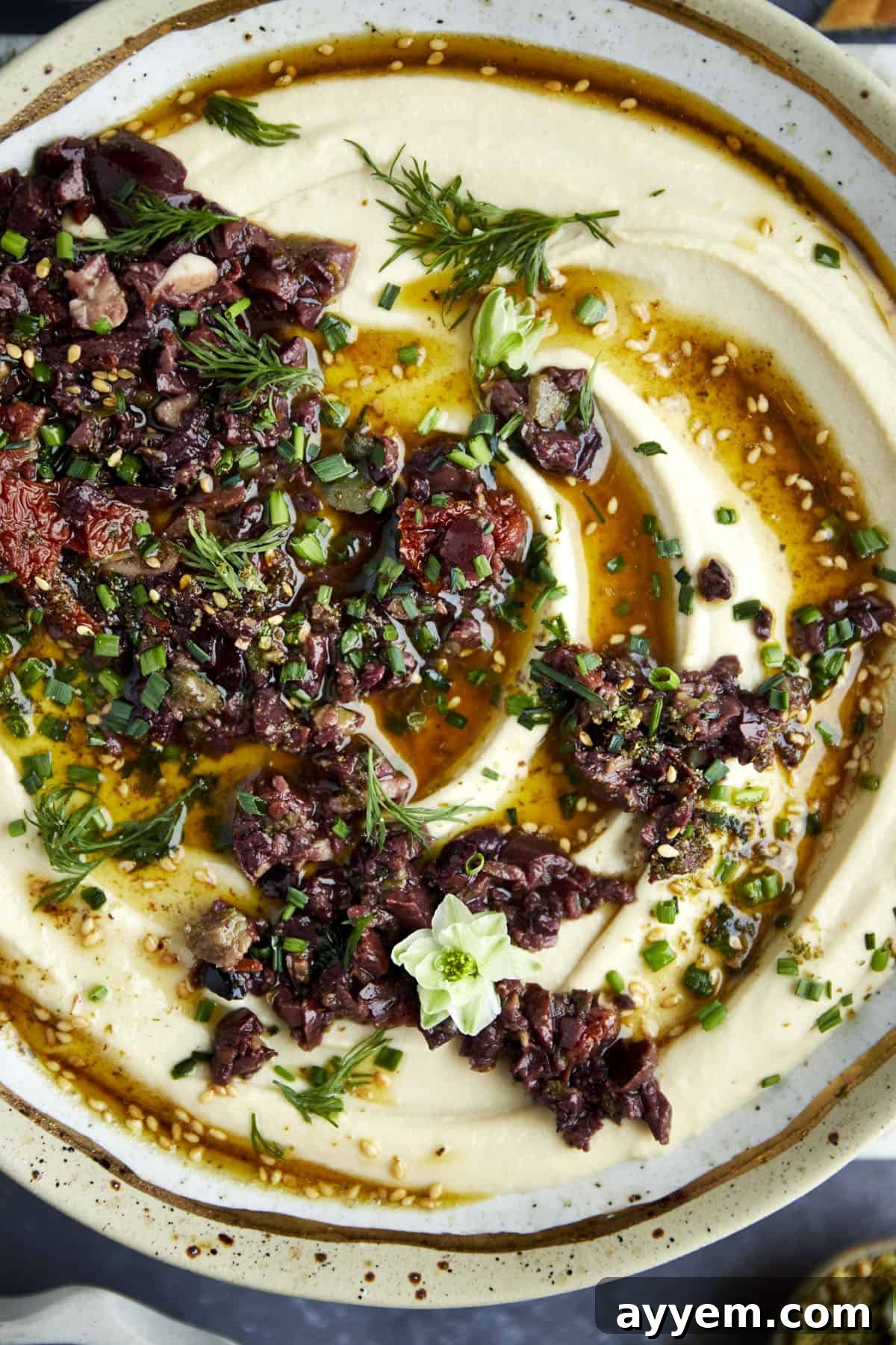 Close-up shot of a richly textured Za'atar Hummus with Olive Tapenade, highlighting the layers of dip.