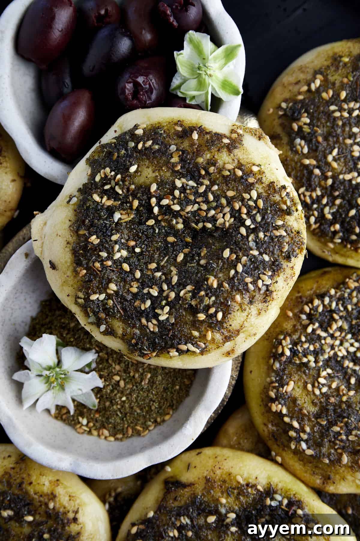 Lebanese Flatbread Wonders 2 Close-up image of a freshly baked Za'atar Manakeesh, showing its golden crust and vibrant green za'atar topping