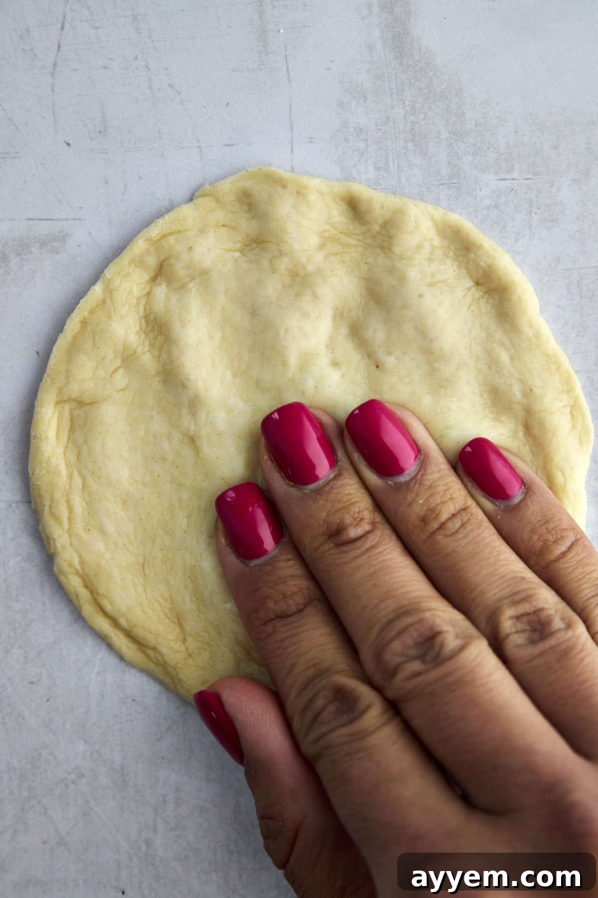 Lebanese Flatbread Wonders 6 Step 3: Gently patting down a risen dinner roll to form a flat disc.