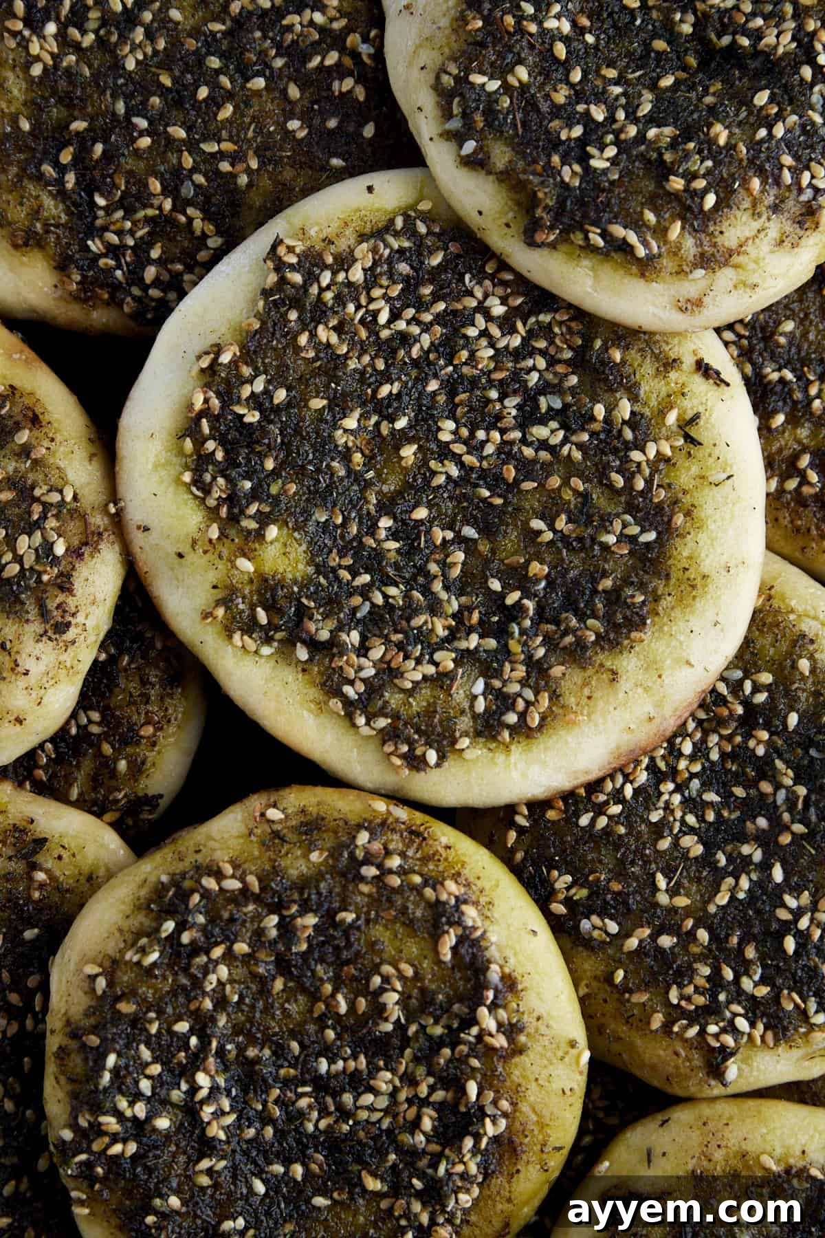Lebanese Flatbread Wonders 8 Individual rounds of Za'atar Manakeesh on a baking sheet, glistening with olive oil and spices