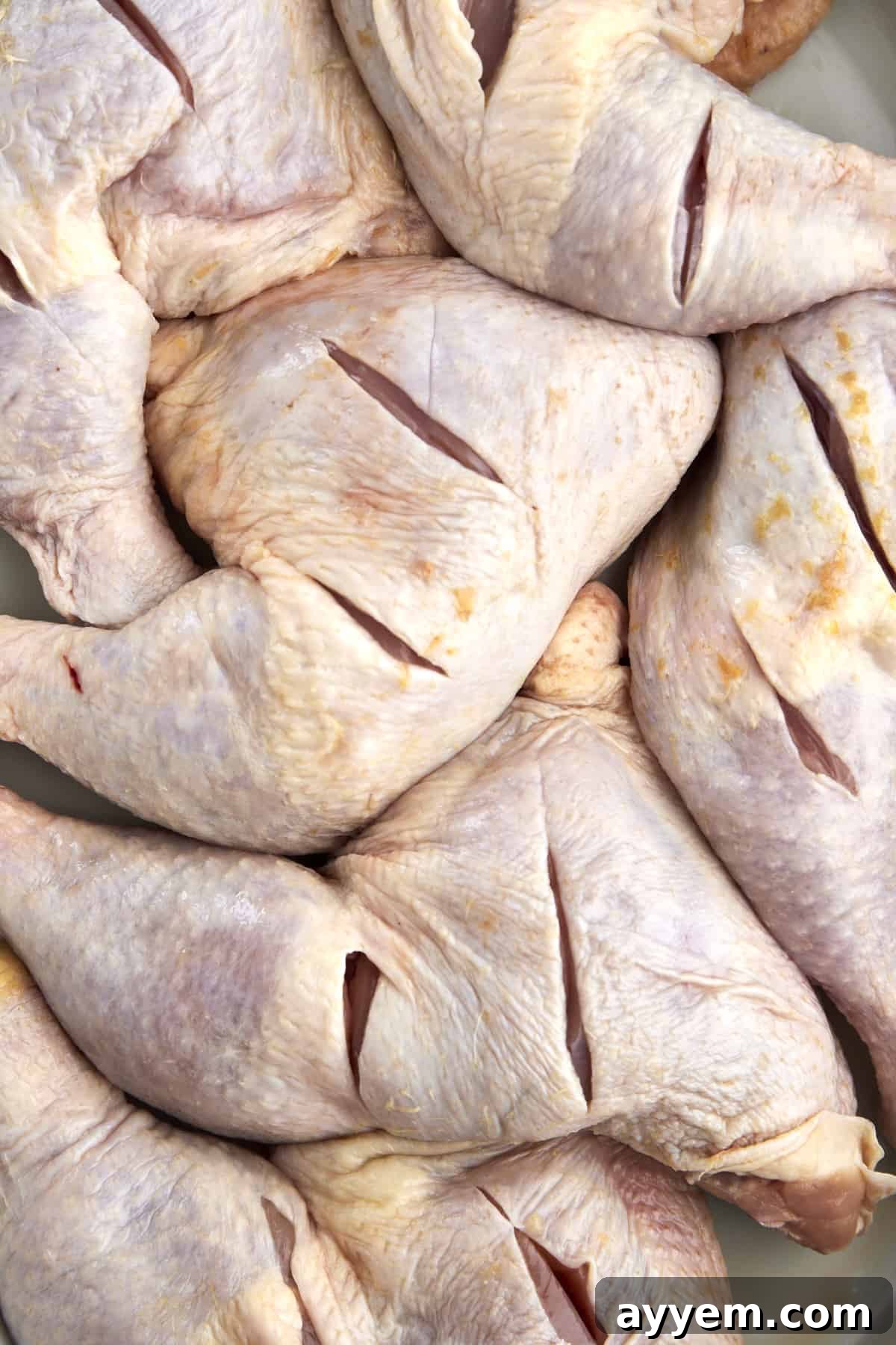 raw chicken legs with slices in them