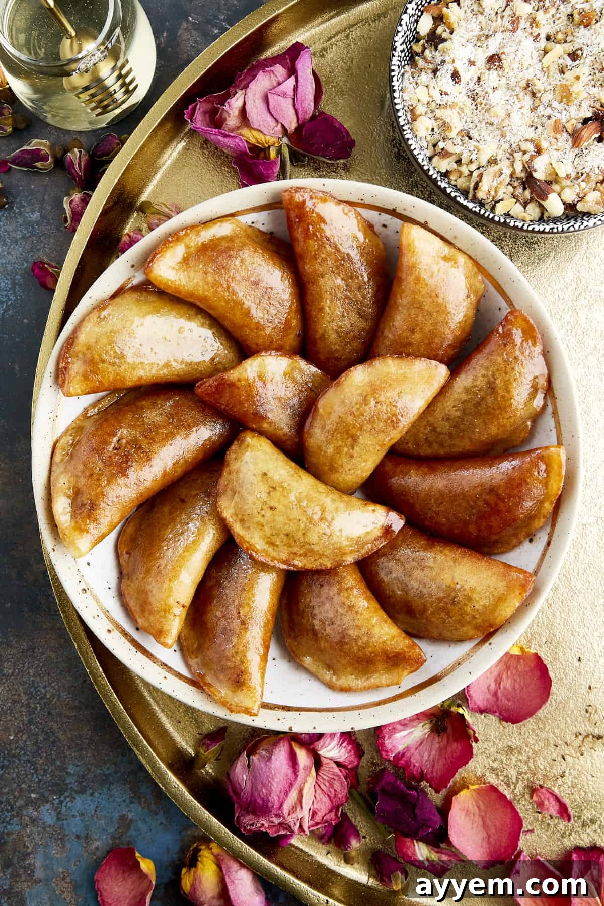 Golden brown Qatayef with a nut filling on a serving platter, drizzled with syrup.