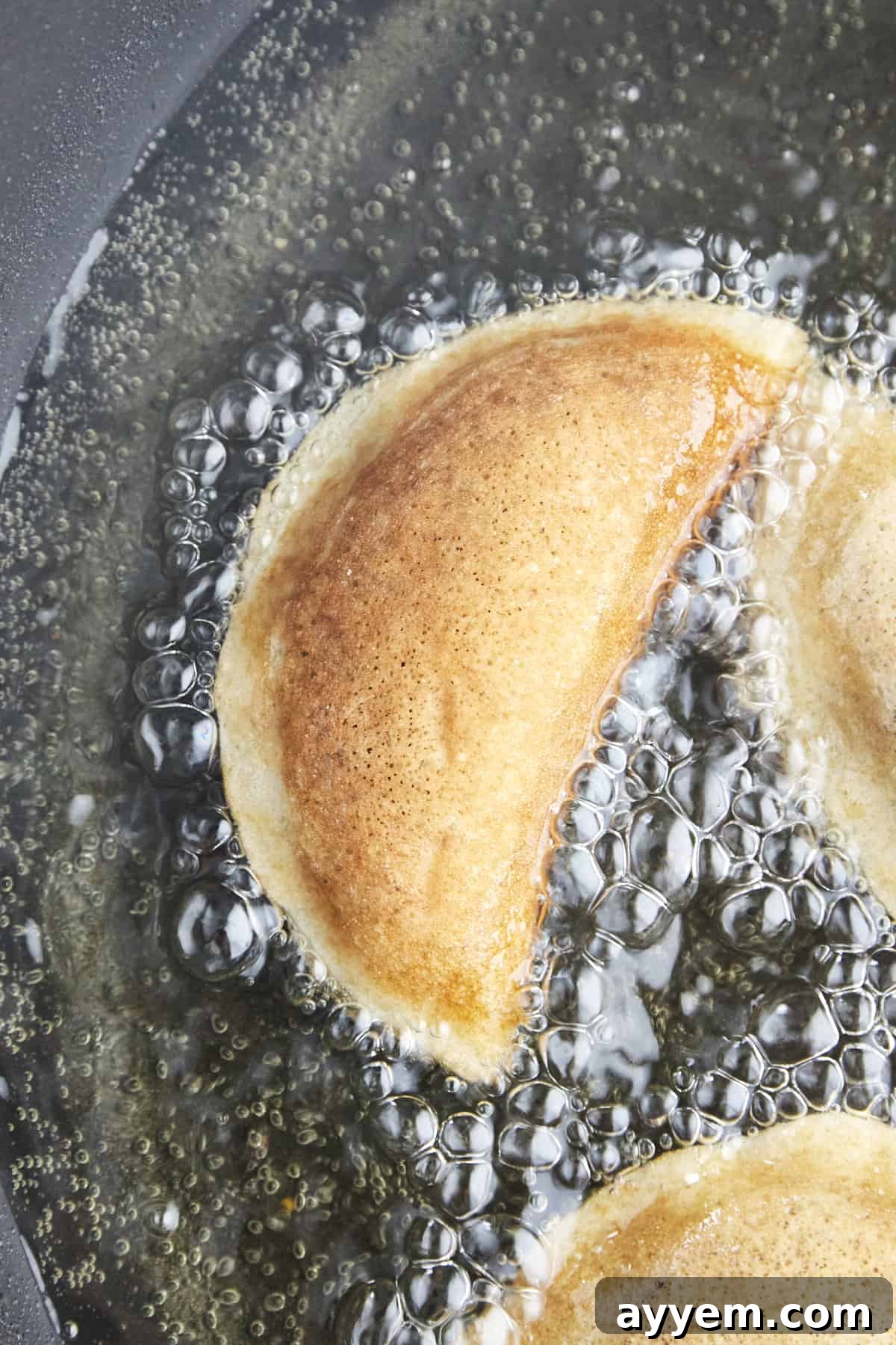 Qatayef pieces frying in hot oil until golden brown.