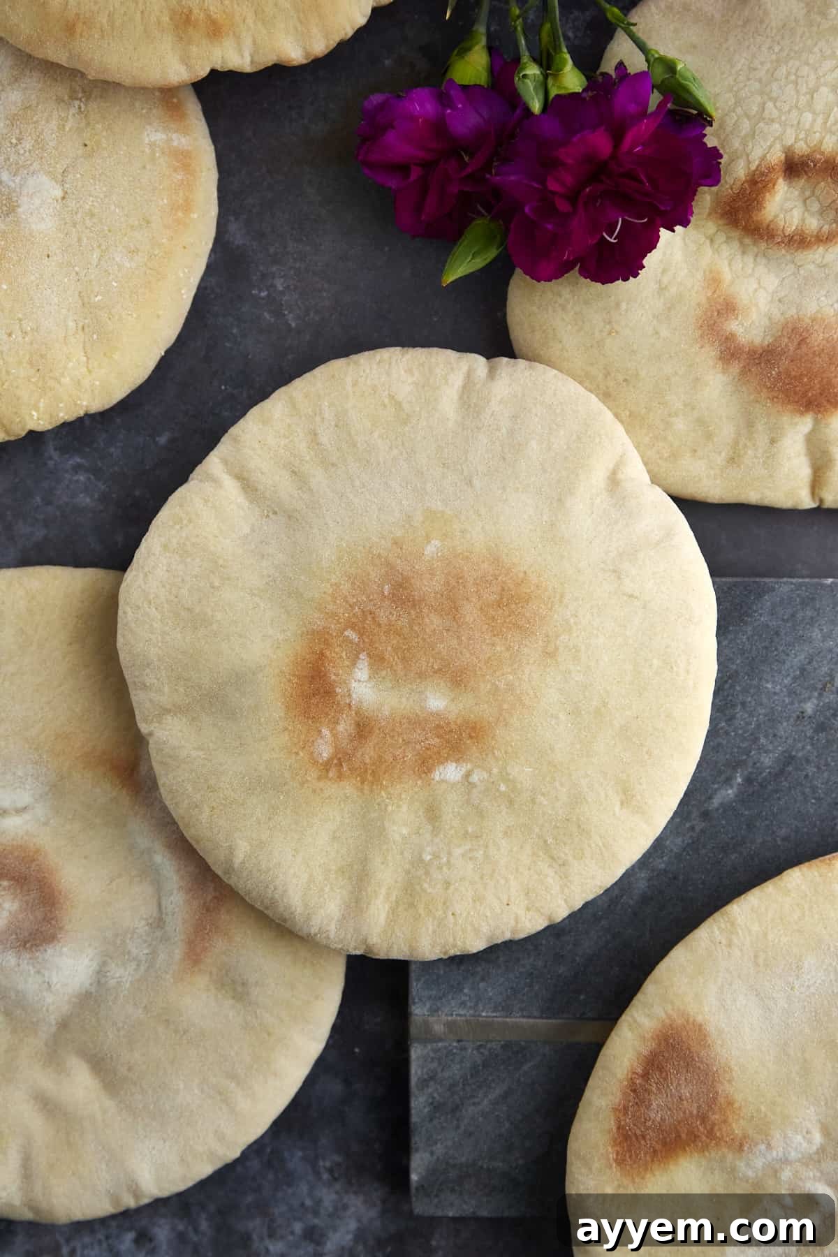An overhead shot of several fluffy white pita bread pockets, ready to be filled.