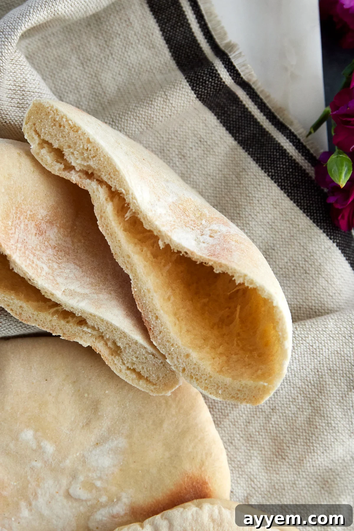 A white pita bread, perfectly split in half to reveal its airy pocket.