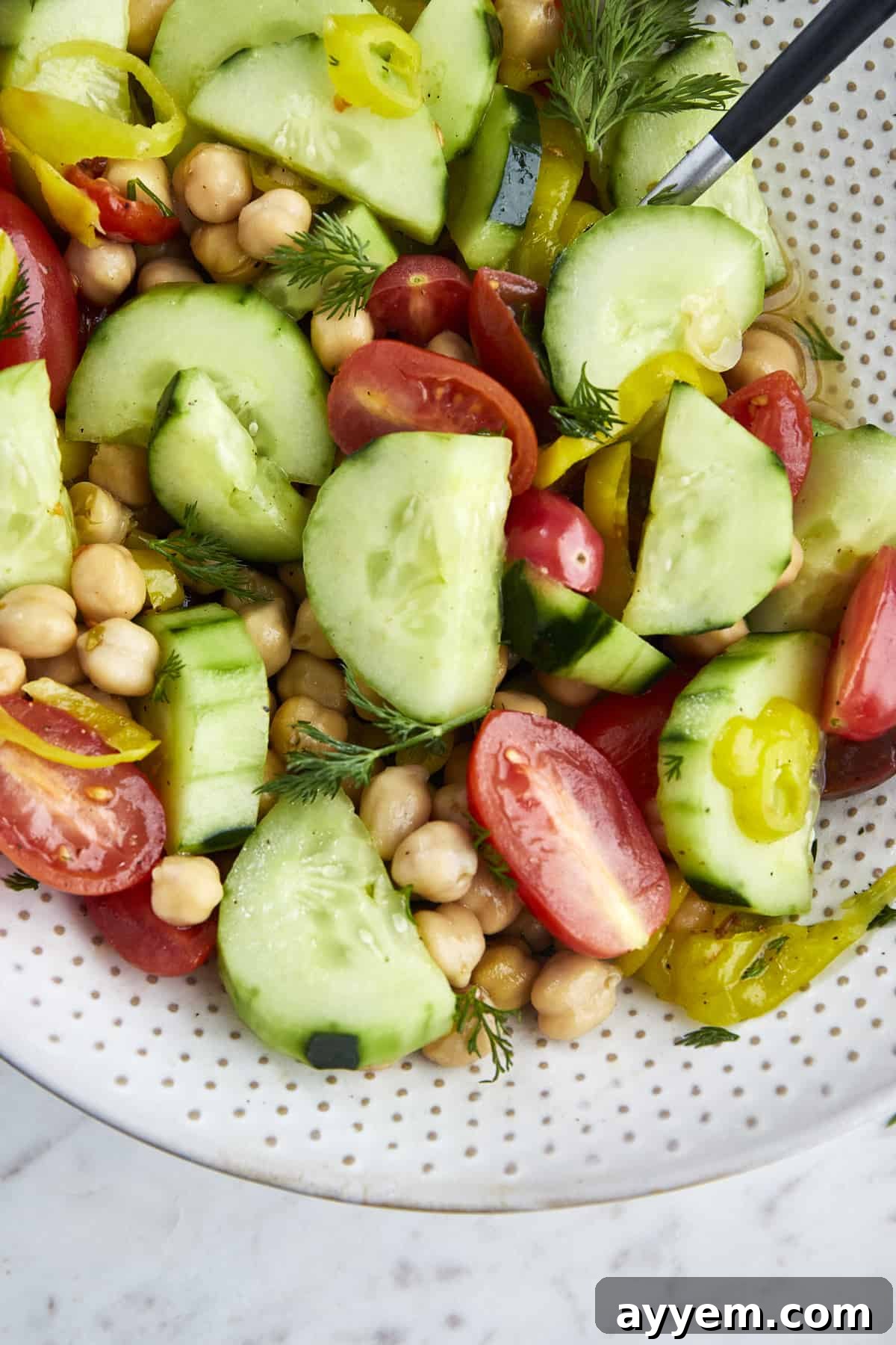 A refreshing side dish of chickpea salad, vibrant with diced tomatoes and crisp cucumbers, perfectly complementing the rich flavors of shawarma chicken.