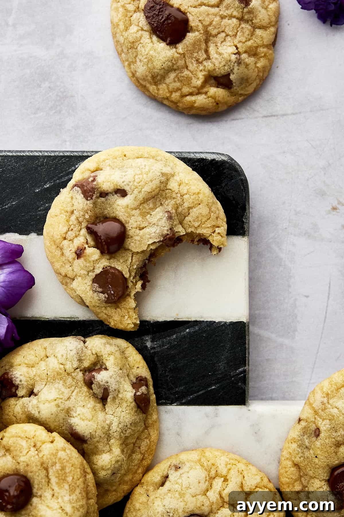 A hand reaching for a mini chocolate chip cookie from a rustic platter, highlighting their tempting appeal.