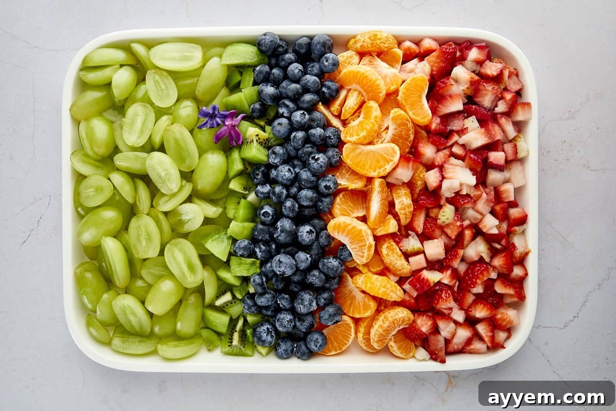 Easy Fruit Salad recipe with fresh blueberries, strawberries, grapes, clementines, kiwis, and mint tossed with a sweet citrus dressing.