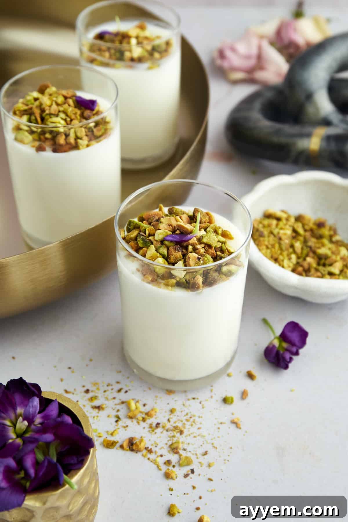 A beautifully garnished Mahalabia dessert in a small glass cup.