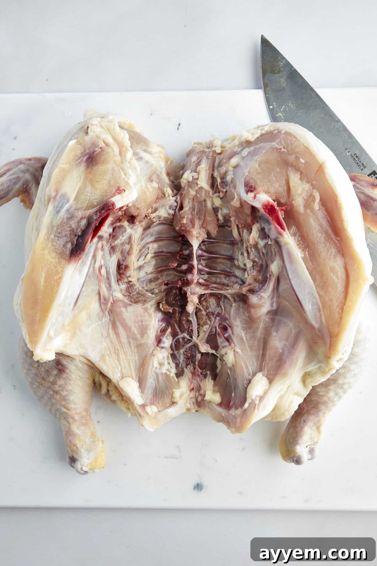 The Art of Roasting a Whole Chicken 7 An open, raw, butterflied chicken flattened on a cutting board, ready for seasoning.