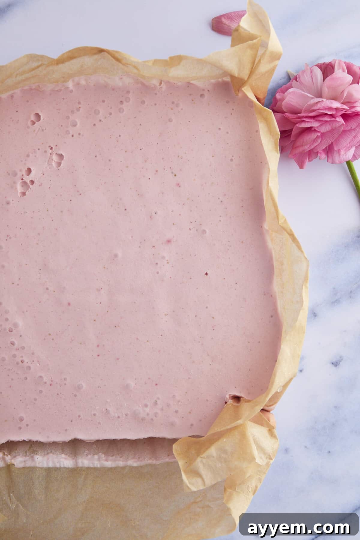 A baking dish filled with chilled no-bake strawberry cheesecake squares, ready to be sliced.