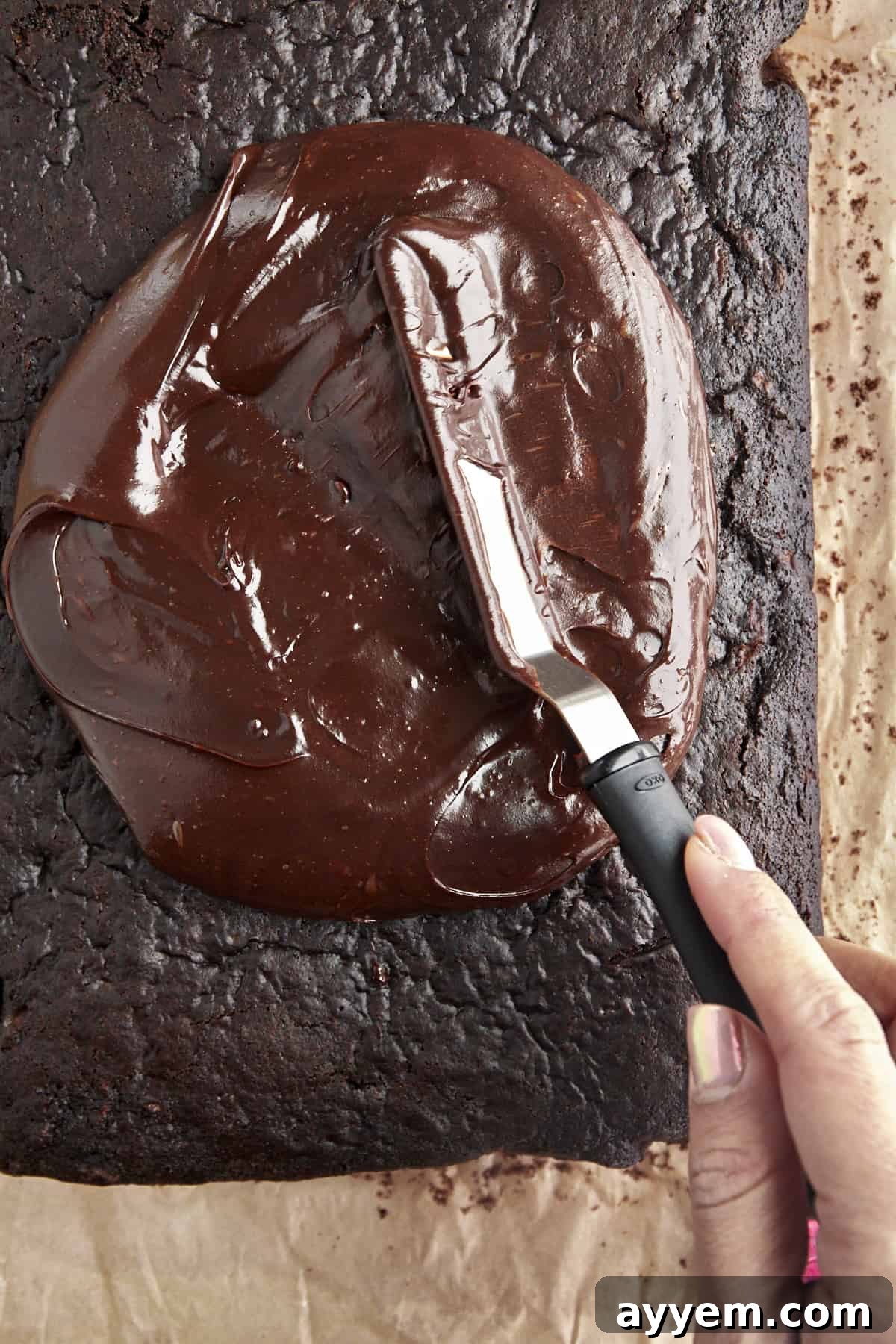 Chocolate frosting being spread evenly over the zucchini cake. 