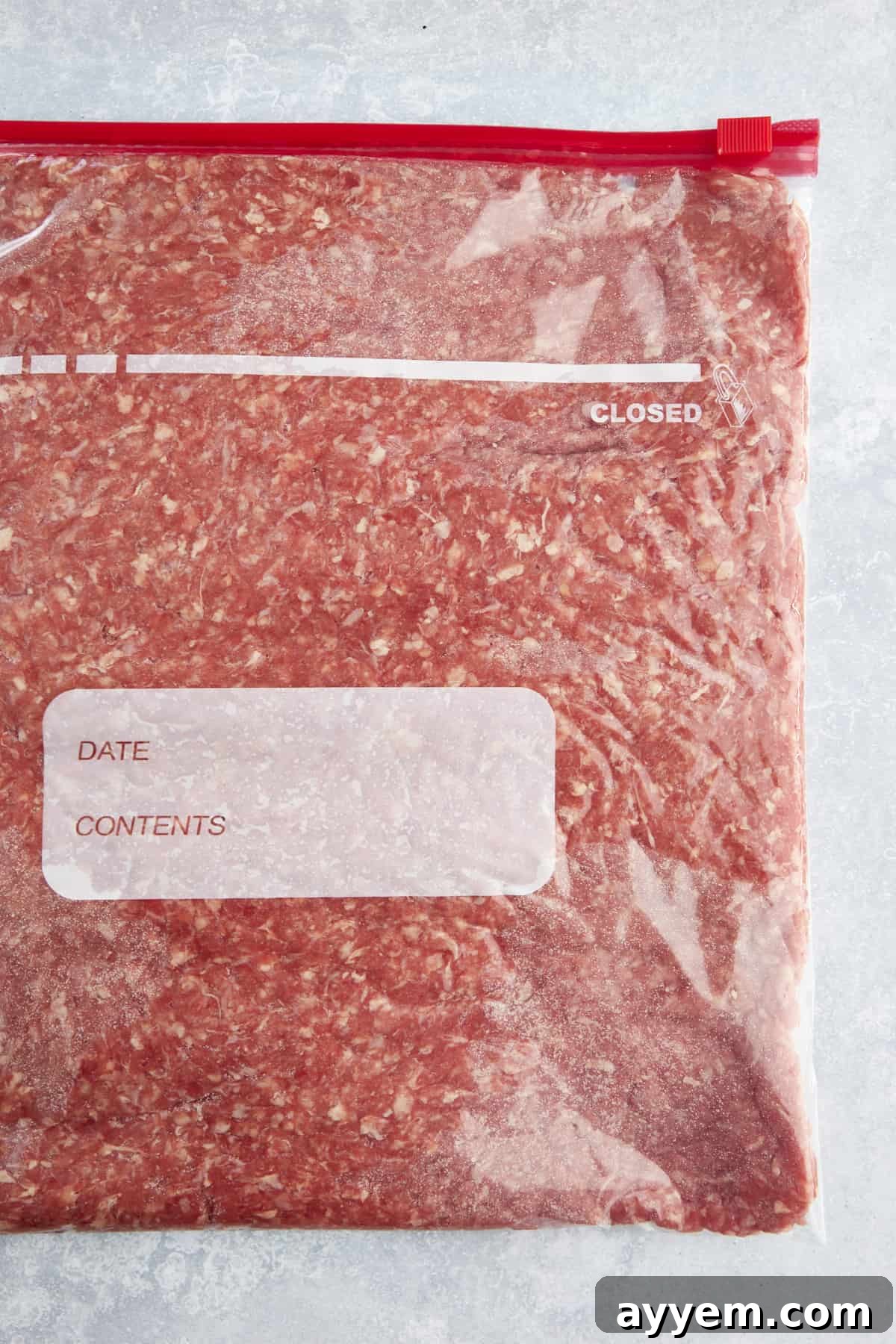 A flattened portion of uncooked ground beef in a sealable Ziploc bag. 