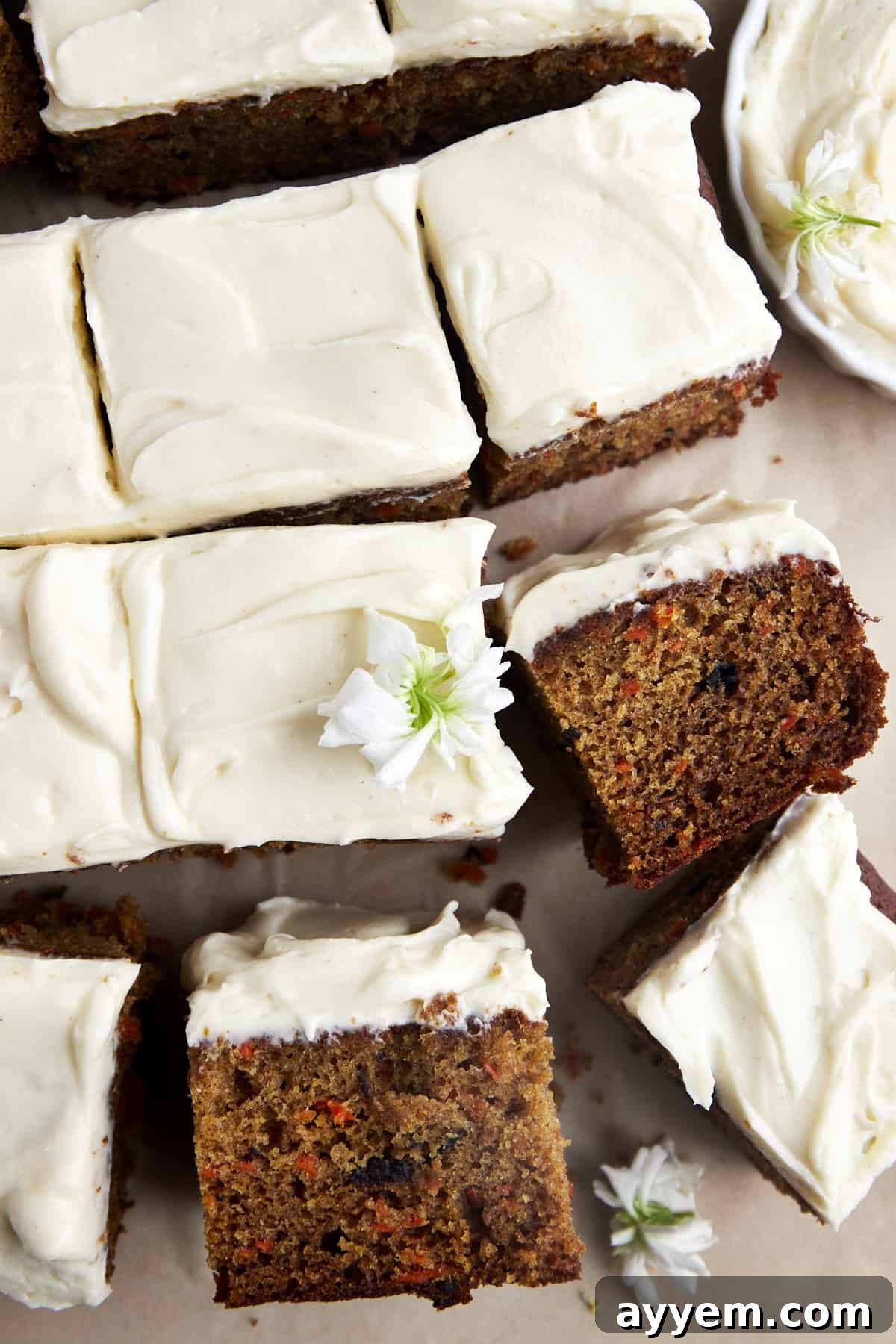Perfectly sliced squares of an easy carrot cake recipe, each topped with a generous swirl of cream cheese frosting.