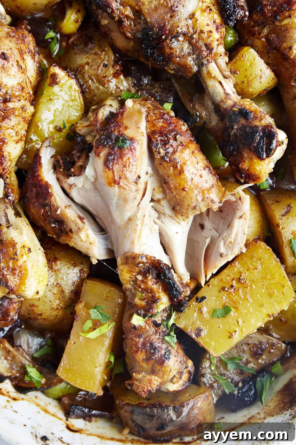Oven baked chicken drumsticks with potatoes exposing the meat. 