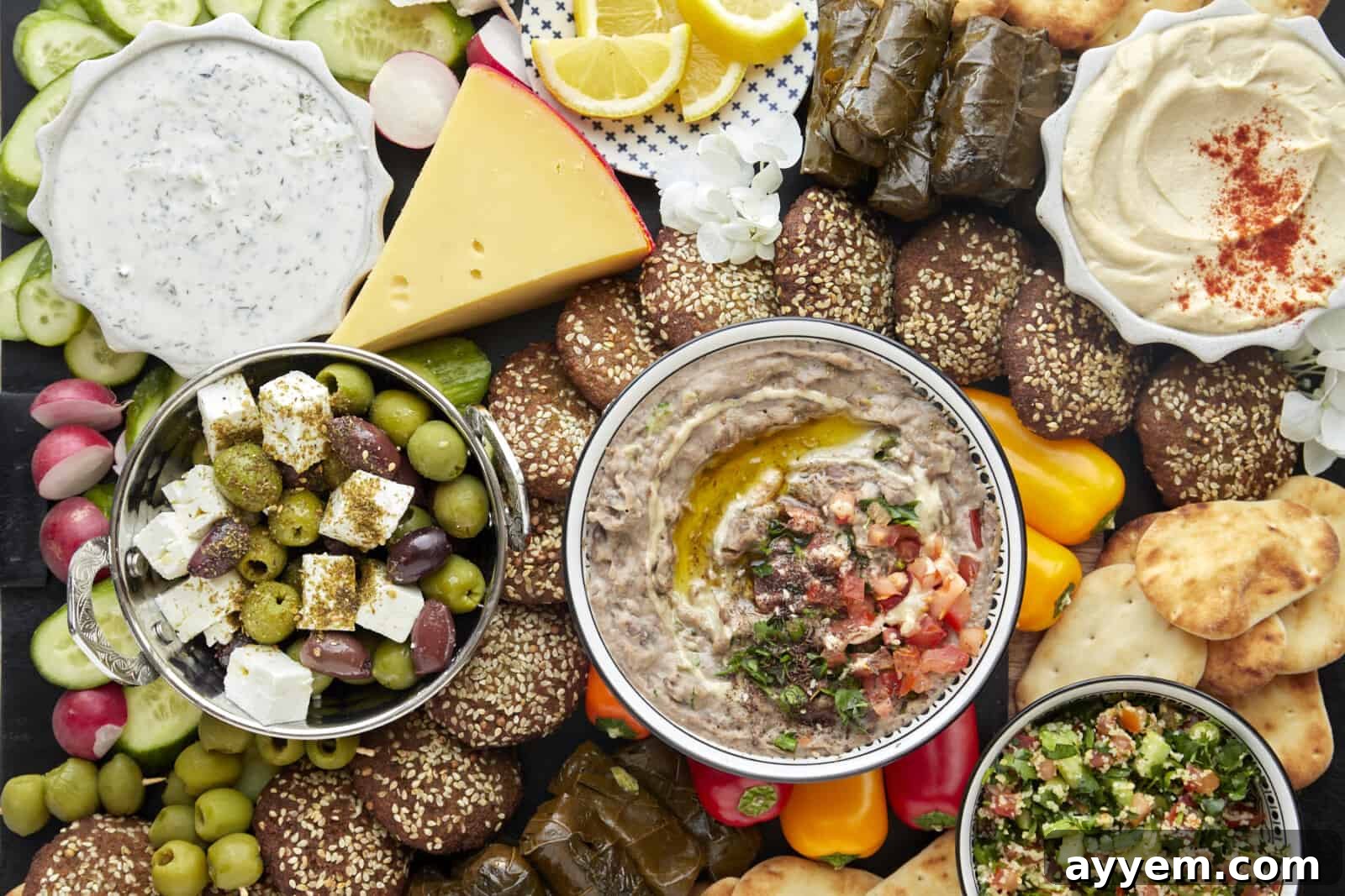Overhead image of a mezze platter with baba ganoush, olives and cheese, and various other appetizers and snacks. 