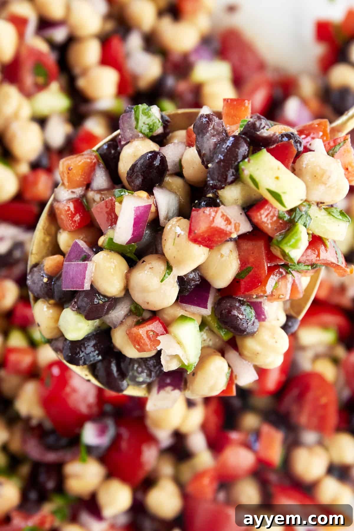 A spoon delicately scooping up a portion of Balela Salad from a bowl, highlighting its fresh ingredients.
