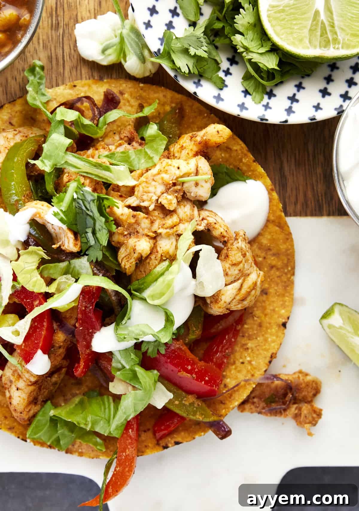 An air fryer chicken fajita taco topped with lettuce, sour cream, and cilantro. 