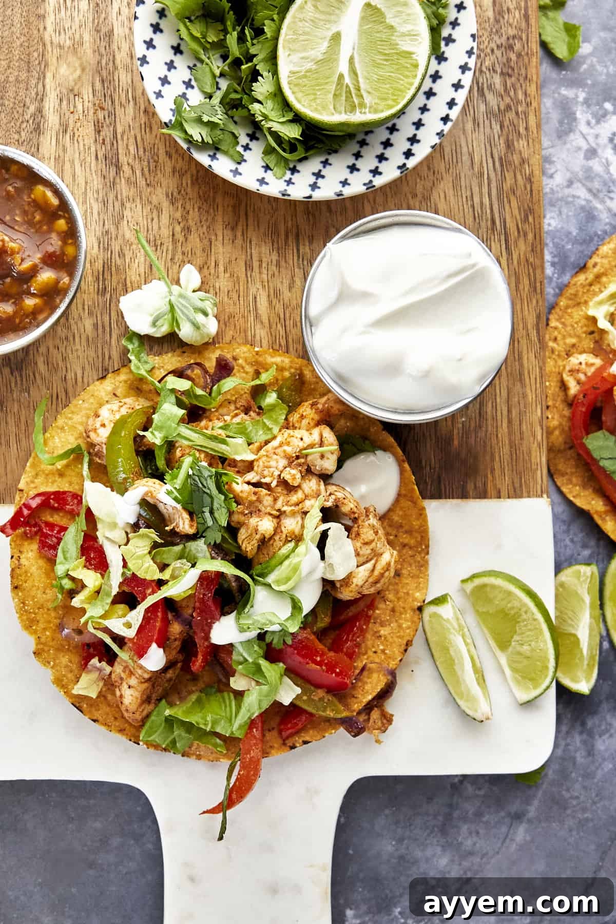 An air fryer chicken fajita taco with sour cream and lime wedges on the side.