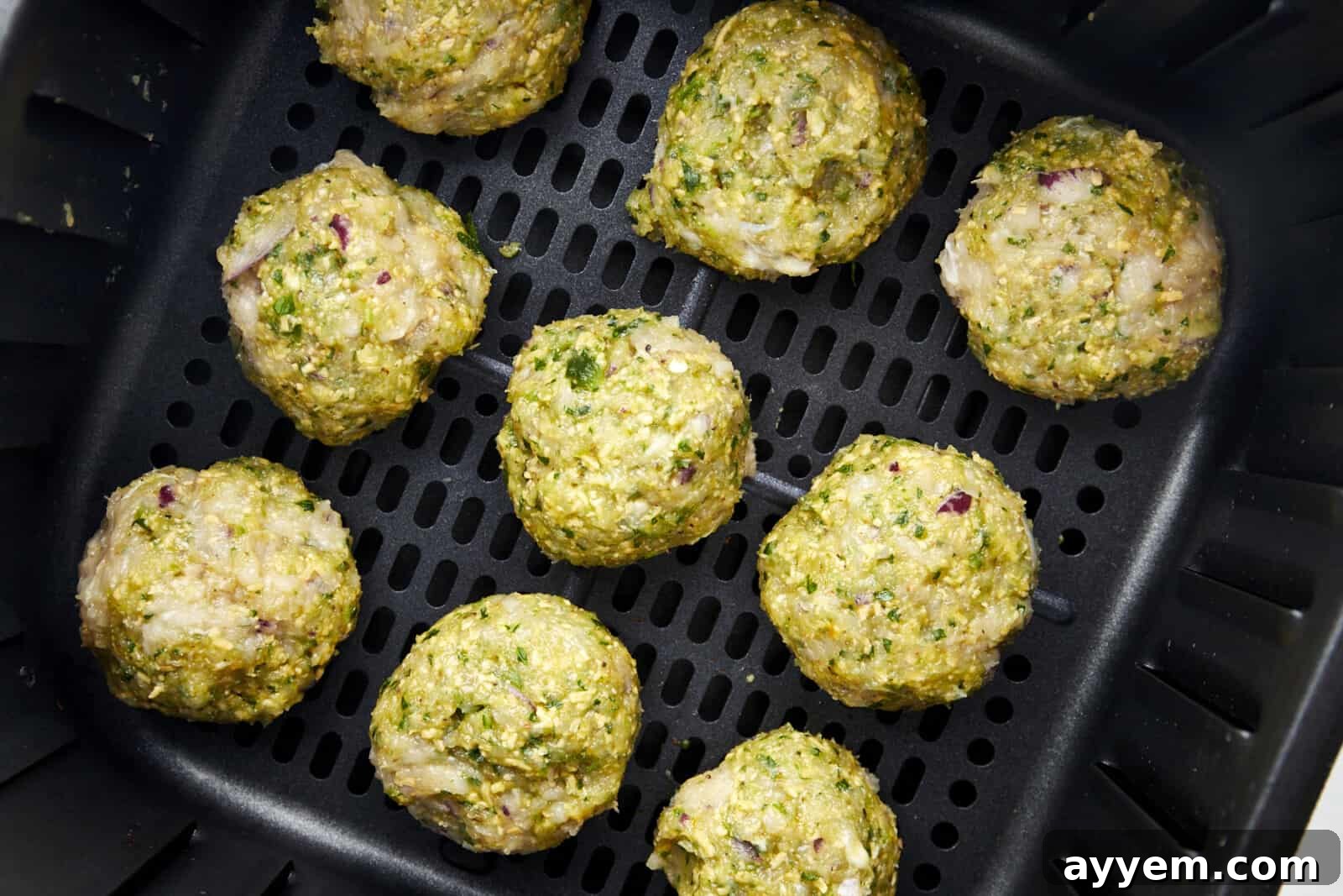 Raw Air Fryer Jalapeño Cheddar Chicken Meatballs in an air fryer basket. 