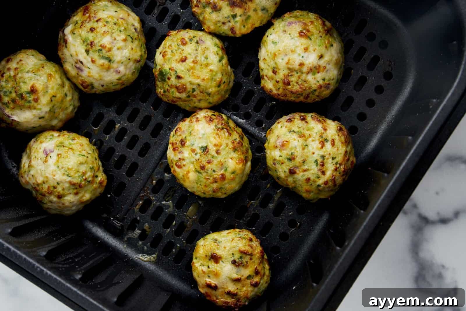 Cooked Air Fryer Jalapeño Cheddar Chicken Meatballs in an air fryer basket. 