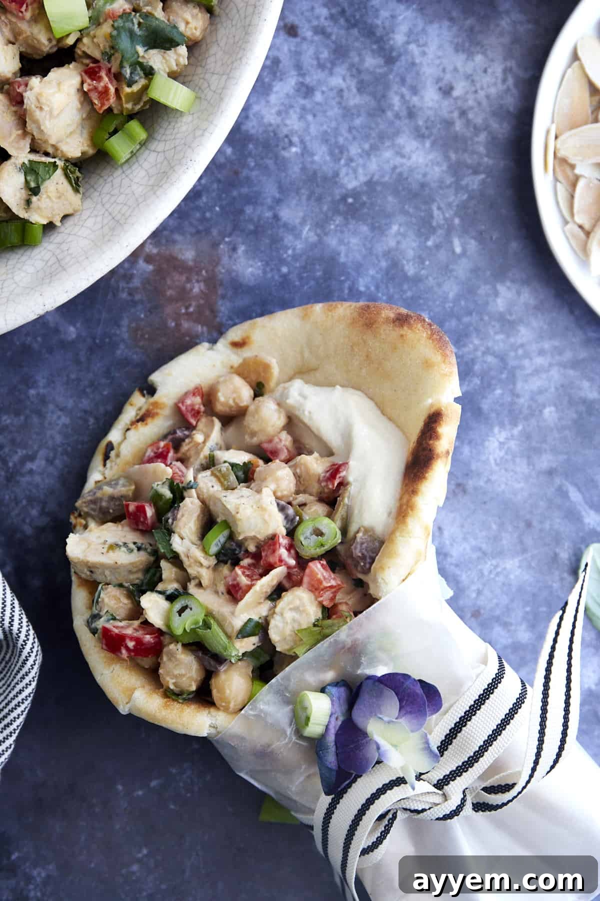 A perfectly prepared pita wrap, generously filled with Chickpea Chicken Salad, is shown sliced in half, revealing the rich textures and vibrant colors of the ingredients within, ready to be enjoyed.