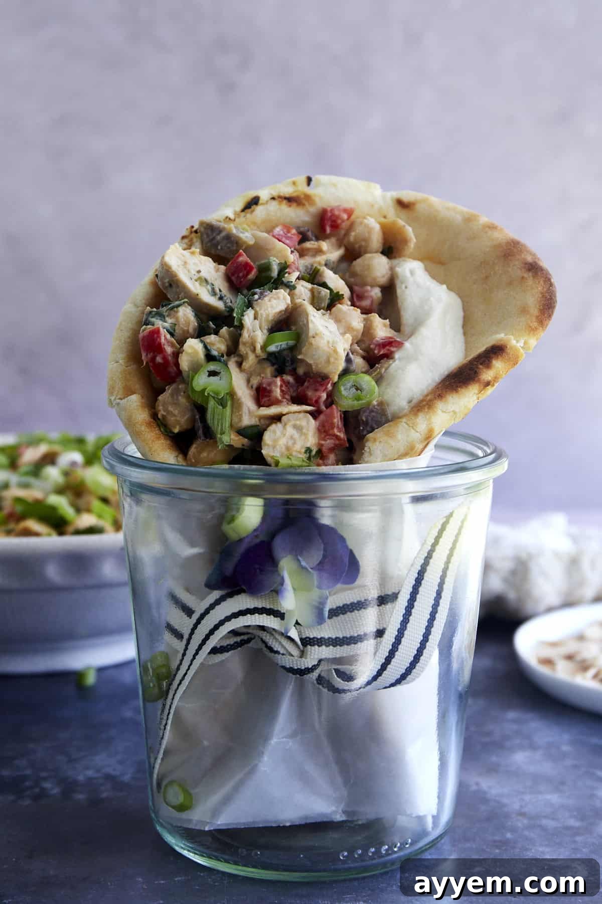 A delectable Chickpea Chicken Salad, elegantly presented with a swirl of creamy hummus, ready to be enjoyed in various ways, from pita wraps to fresh lettuce cups.