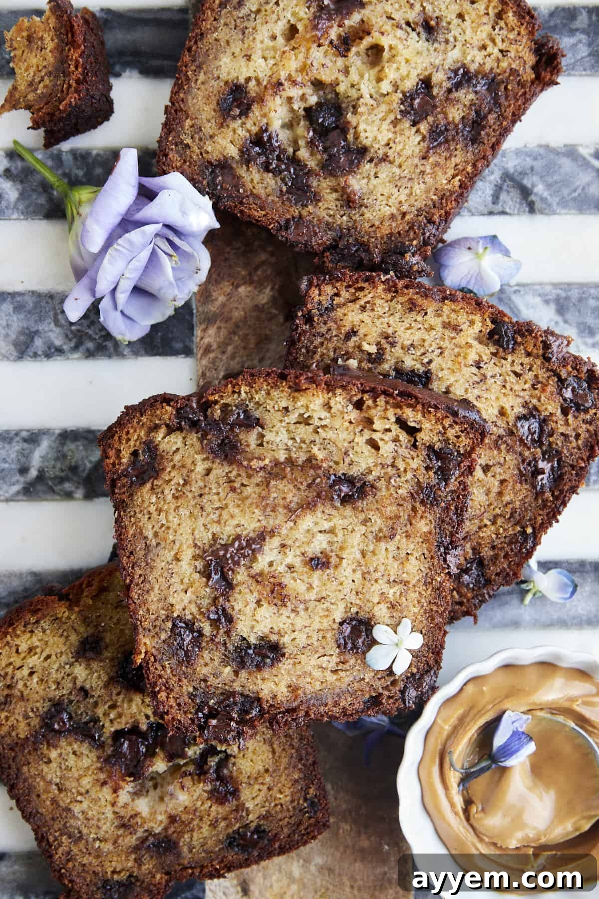 Irresistible Chocolate Chip Peanut Butter Banana Bread 4 Multiple slices of freshly baked chocolate chip peanut butter banana bread arranged artfully on a plate, with a small bowl of creamy peanut butter on the side for serving.