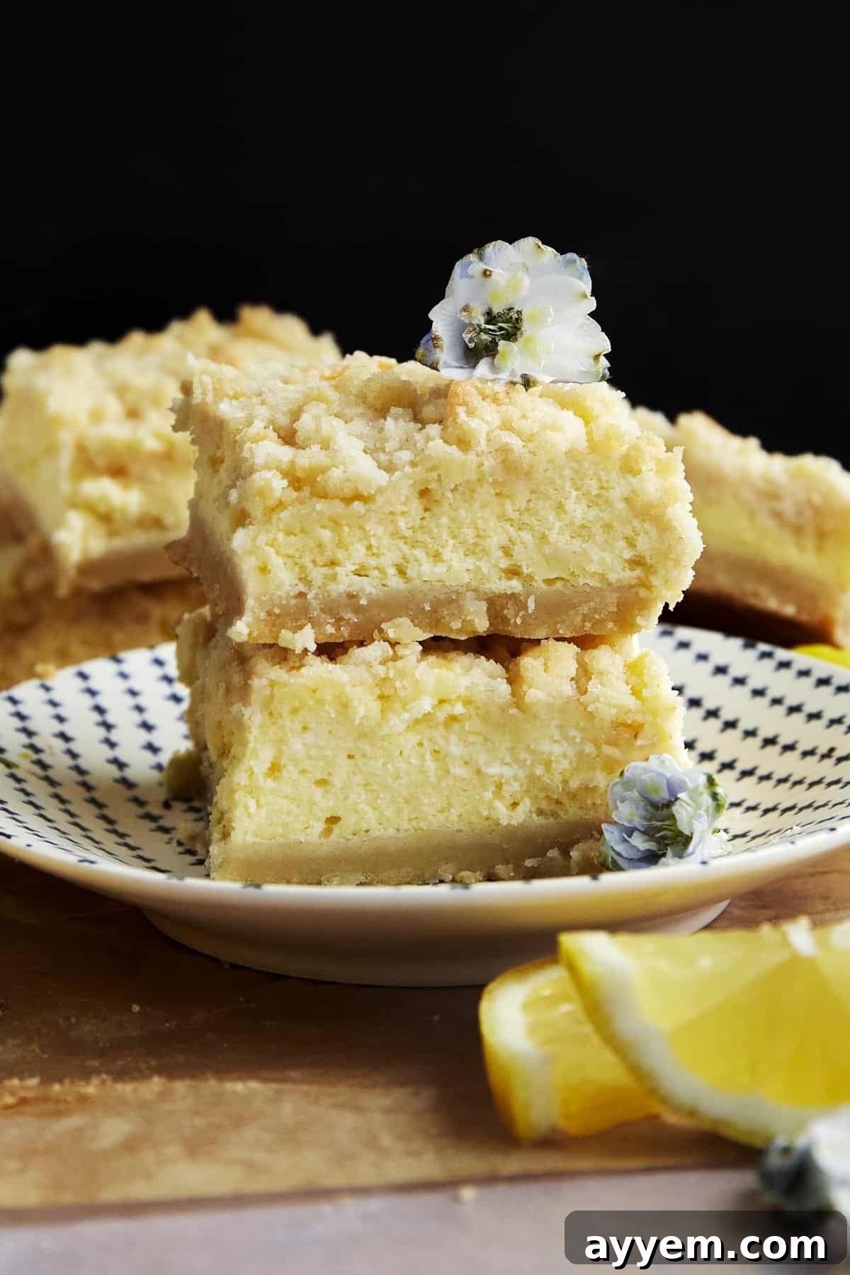 Two vibrant lemon cheesecake bars stacked elegantly on a white plate, ready to be enjoyed.