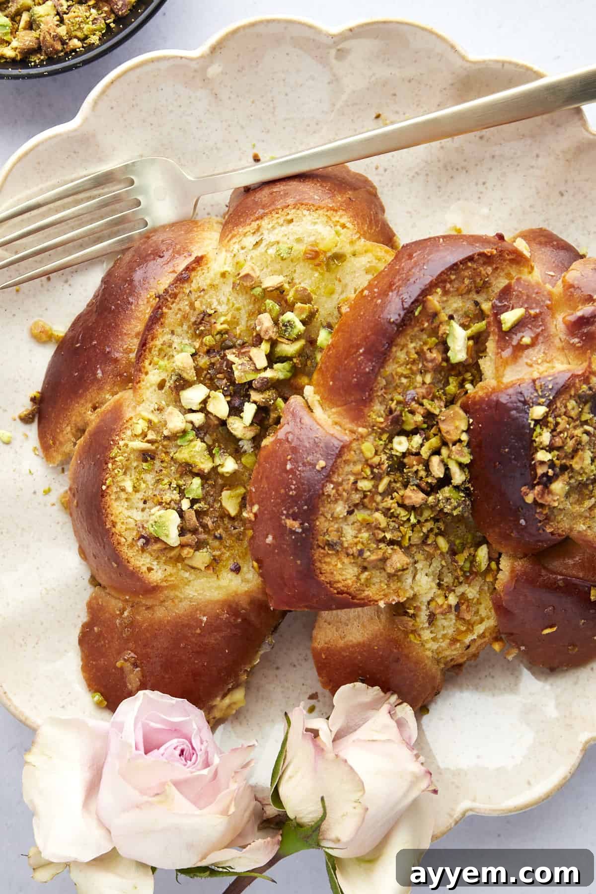 A generous serving of Baklava Challah French Toast on a elegant white plate, drizzled with syrup and garnished.