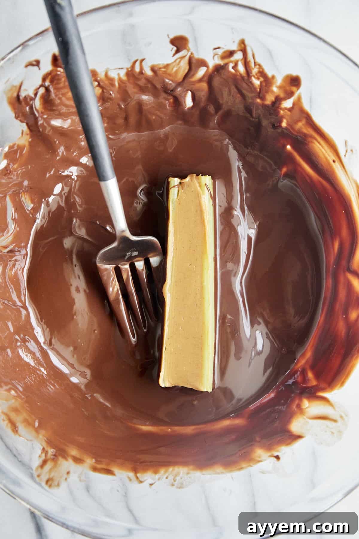 A peanut butter stuffed celery stick being carefully rolled in a bowl of melted, glossy chocolate. This image captures the indulgence of the recipe.