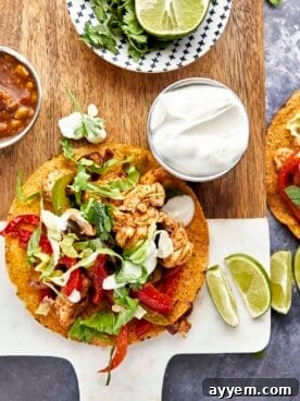 An air fryer chicken fajita taco, garnished with fresh lime and sour cream, on a plate.
