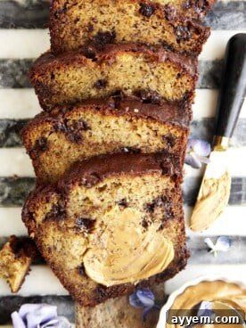 Slices of chocolate chip peanut butter banana bread with a piece smeared with peanut butter.