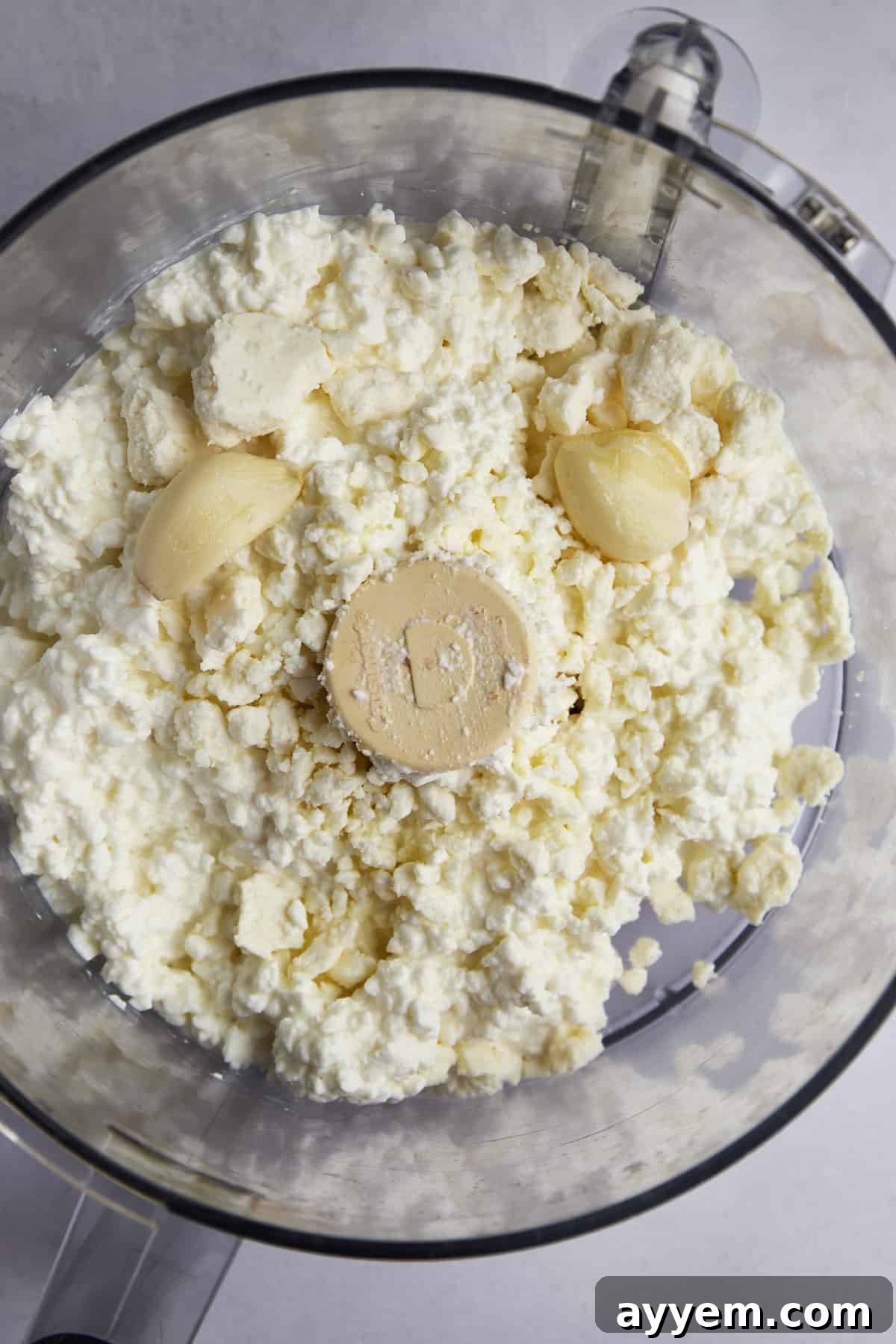 Anatolian Poached Eggs with Cottage Cheese 3 Cottage cheese, feta, and garlic cloves in a food processor, ready to be blended for the creamy base.