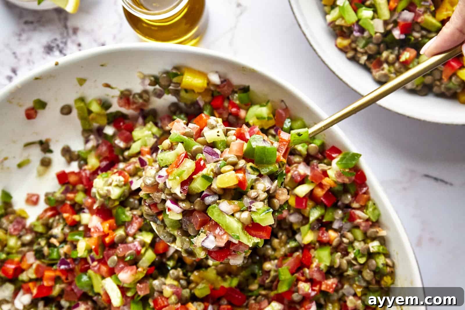 A serving spoon lifting a scoop of vibrant lentil mango salad, showing the mix of crisp vegetables, sweet mango, and hearty lentils.