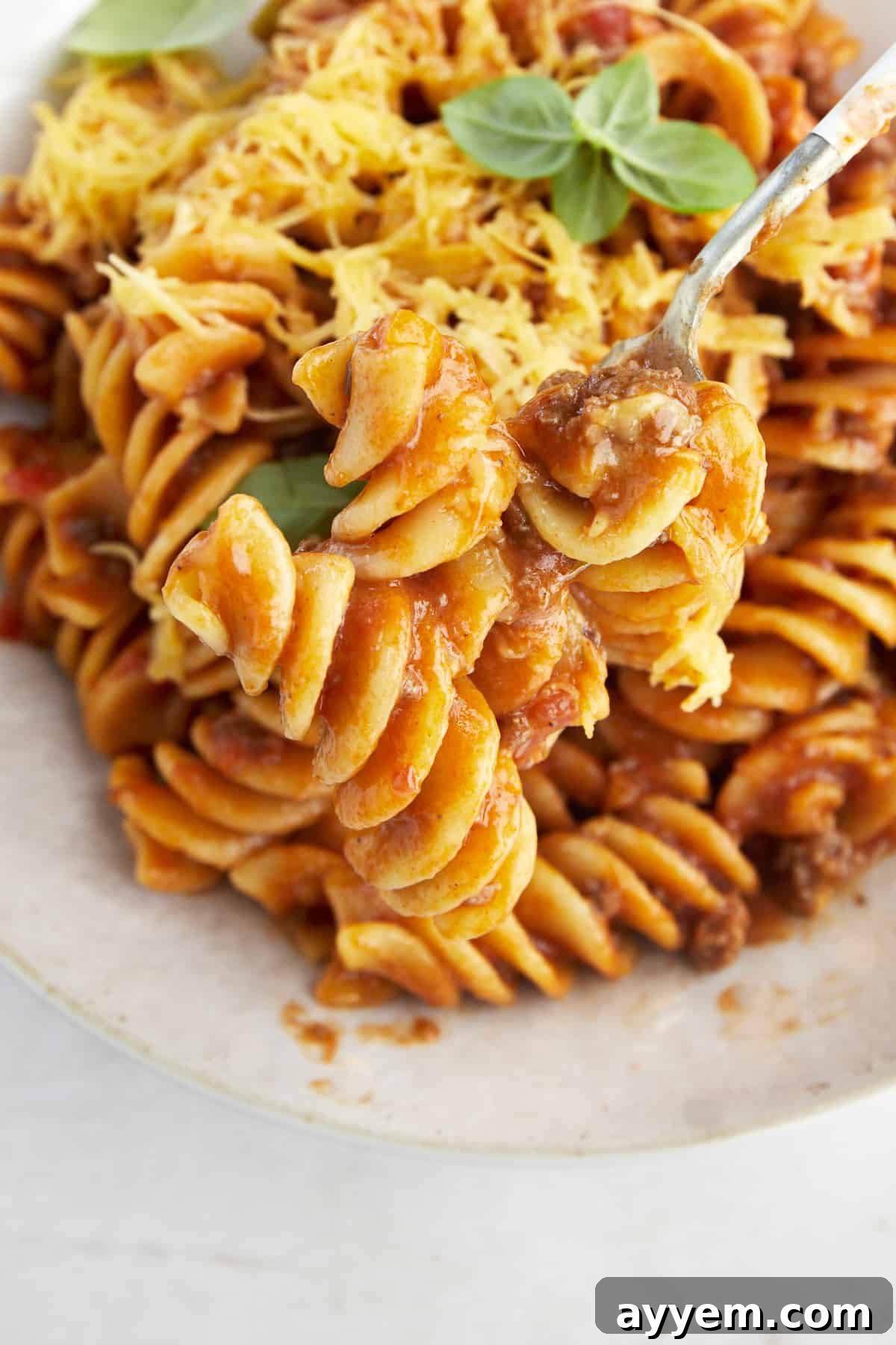 A fork holding a bite of taco pasta with beef. 