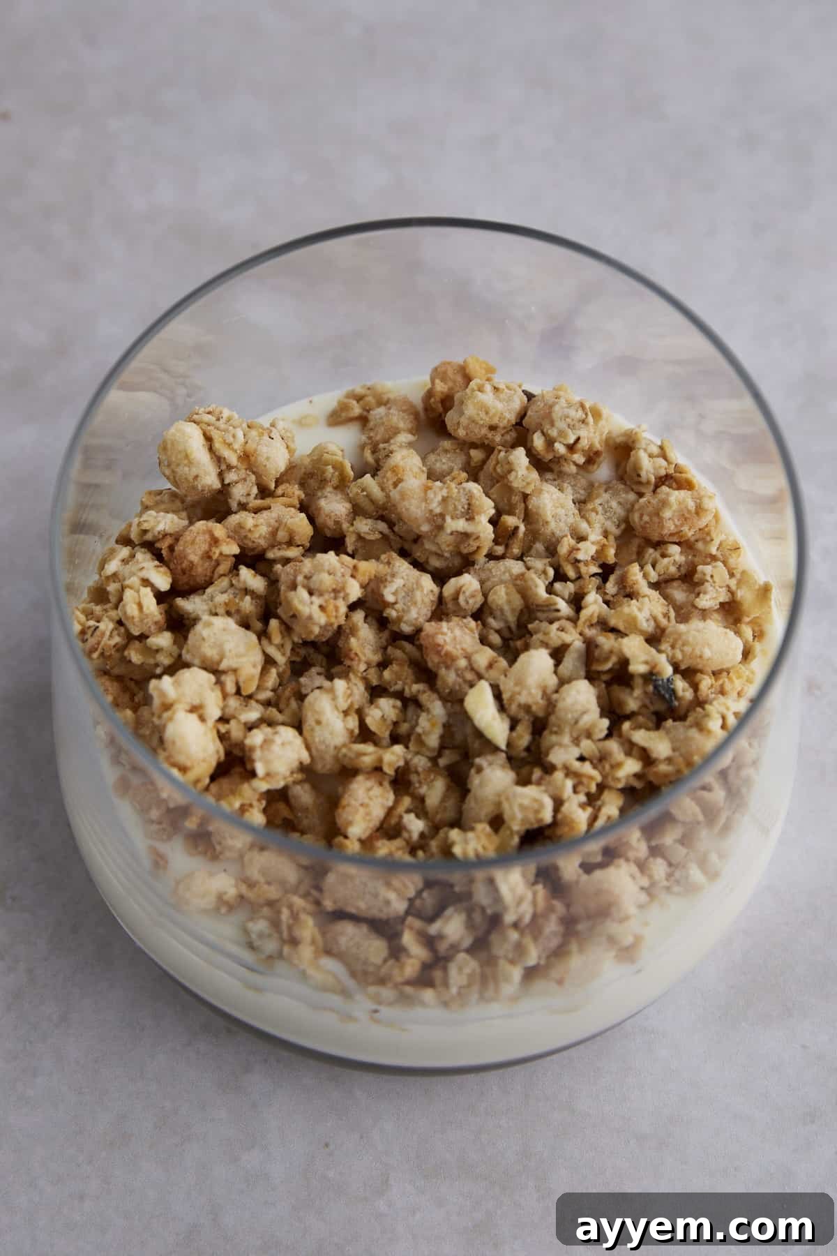Granola layered on top of yogurt in a glass jar, adding a crunchy texture to the parfait.