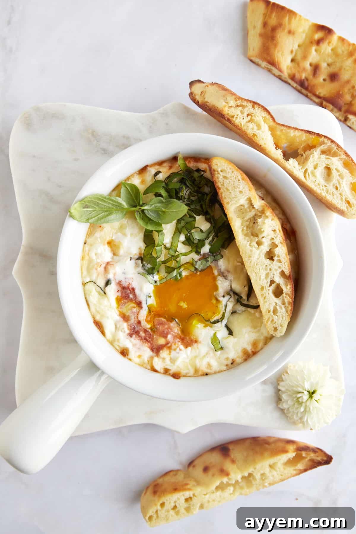 Easy Italian Baked Eggs Purgatorio 4 An egg yolk running over a ramekin full of Eggs in Purgatory with bread on the side.