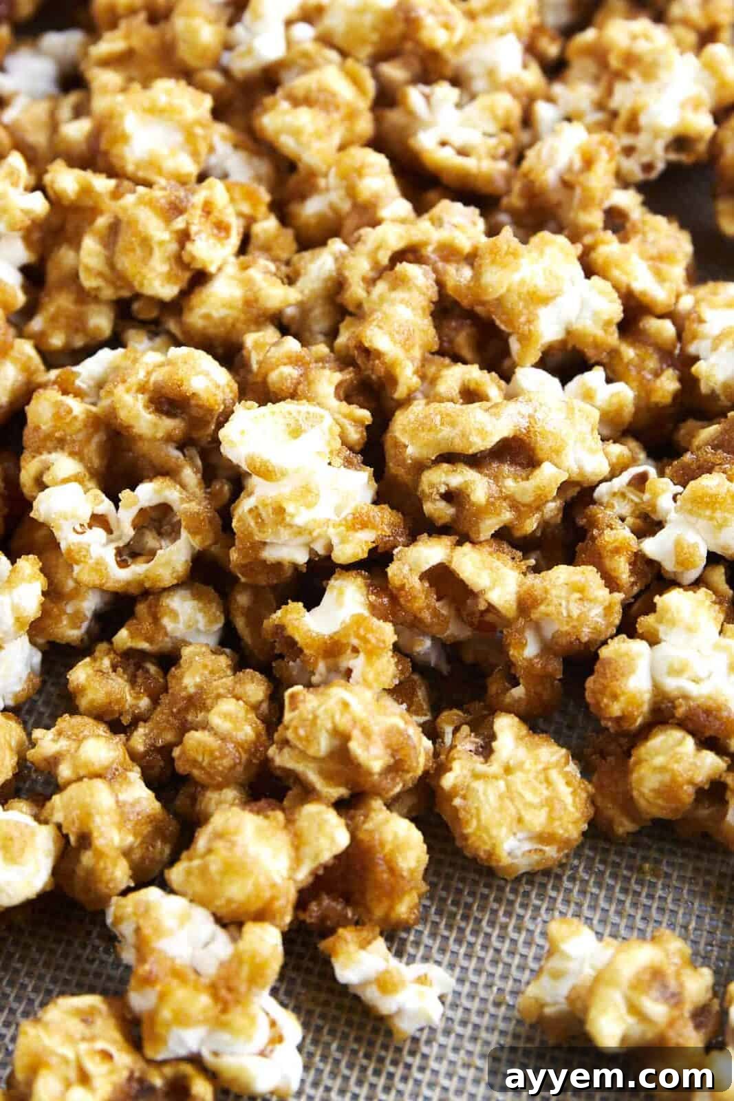A close-up image of homemade caramel popcorn scattered on a baking sheet, highlighting its shiny, golden caramel coating.