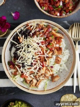 A homemade chipotle bowl with rice, chicken, lettuce, salsa, black beans, and cheese