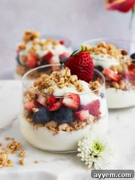 Three jars of fruit and yogurt parfait with blueberries, strawberries, and granola.