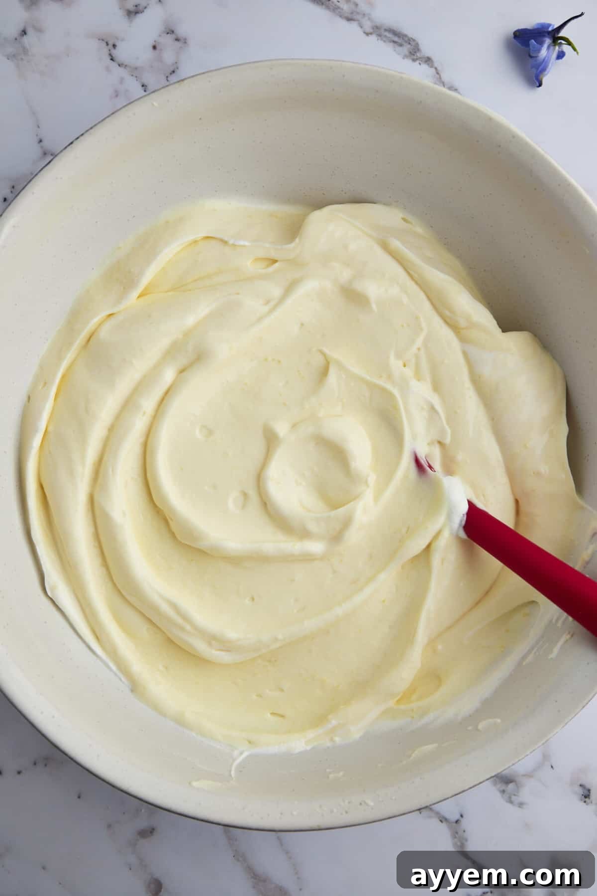 An overhead shot of a bowl filled with creamy, pudding-enhanced whipped topping, ready for layering.