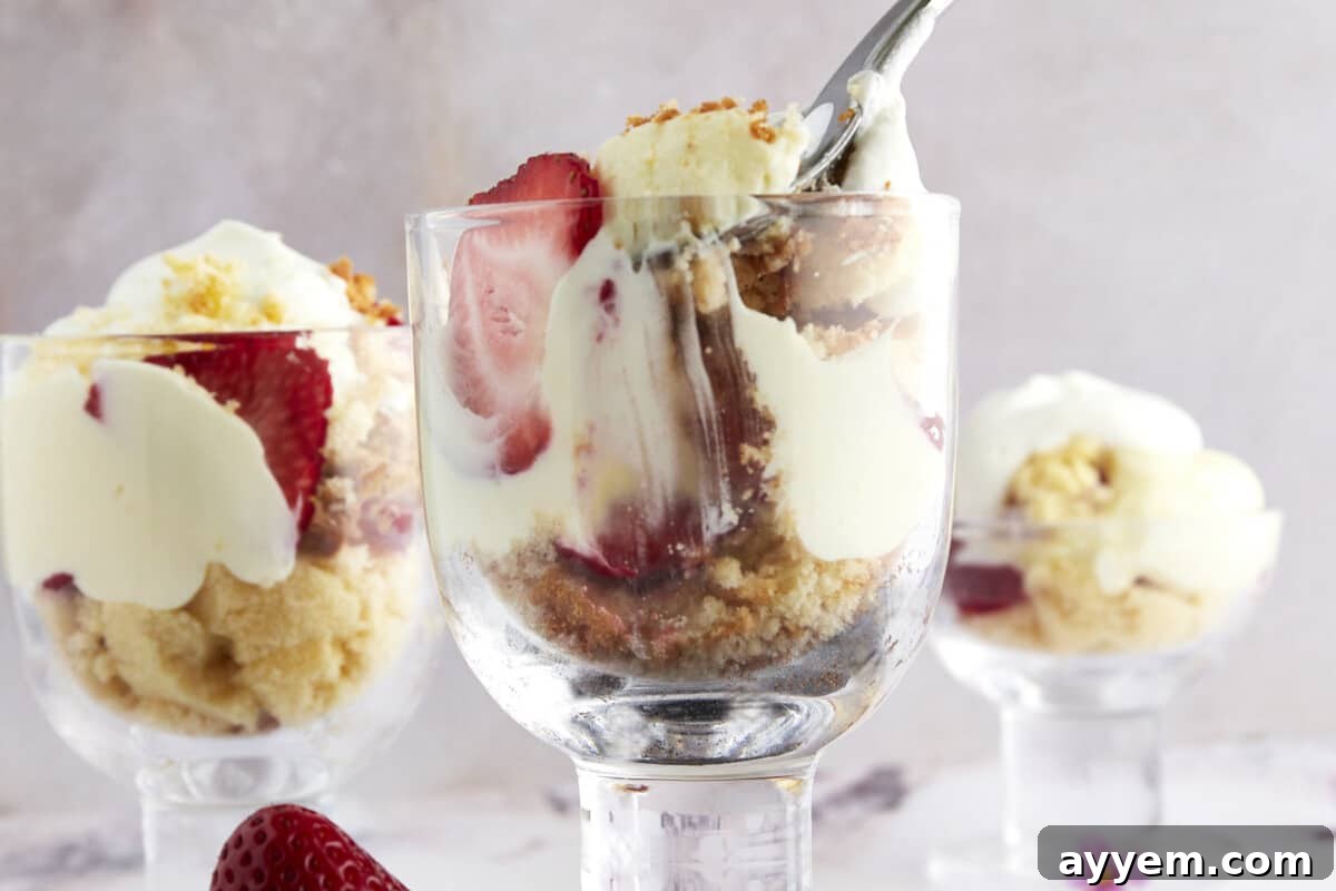 Three individual strawberry shortcake shooters arranged beautifully, with one having a fork taking a delightful bite.