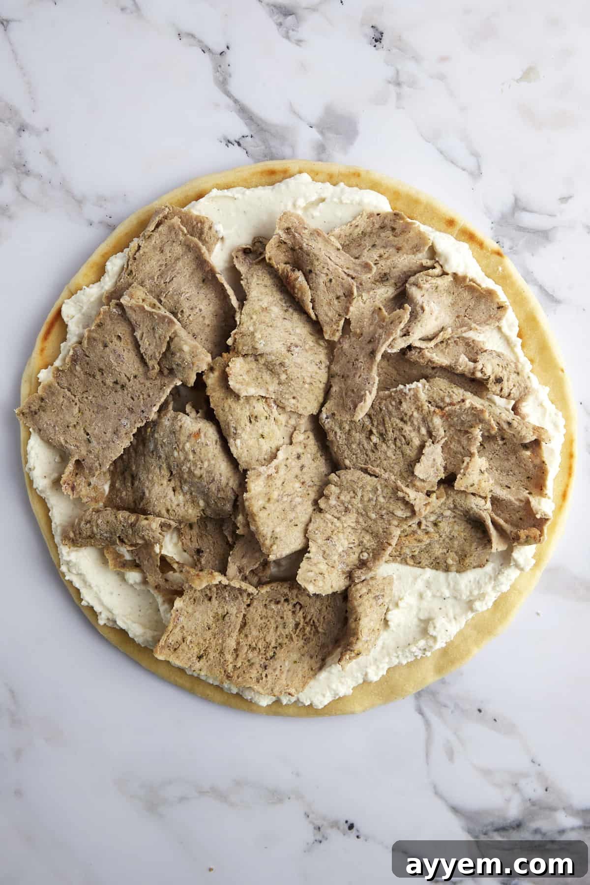 Pizza crust topped with a layer of whipped feta and then generously scattered with savory shredded gyro meat.